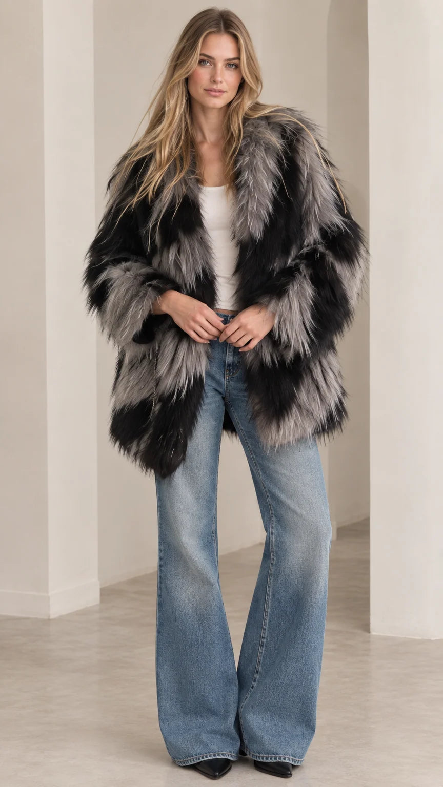 Front view of model wearing black and grey chevron shaggy faux fur coat with flare jeans