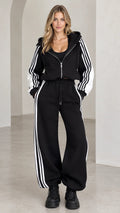 Front view of model wearing black cropped zip hoodie and wide-leg striped tracksuit set