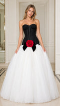 Front view of model wearing black and white strapless corset ball gown with red rose accent