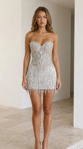 Front view of model wearing silver strapless rhinestone fringe mini dress