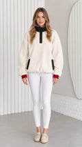 Front view of model wearing cream sherpa fleece pullover with black mock neck and white leggings