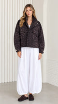 Front view of model wearing dark brown leopard print cropped jacket with wide white trousers