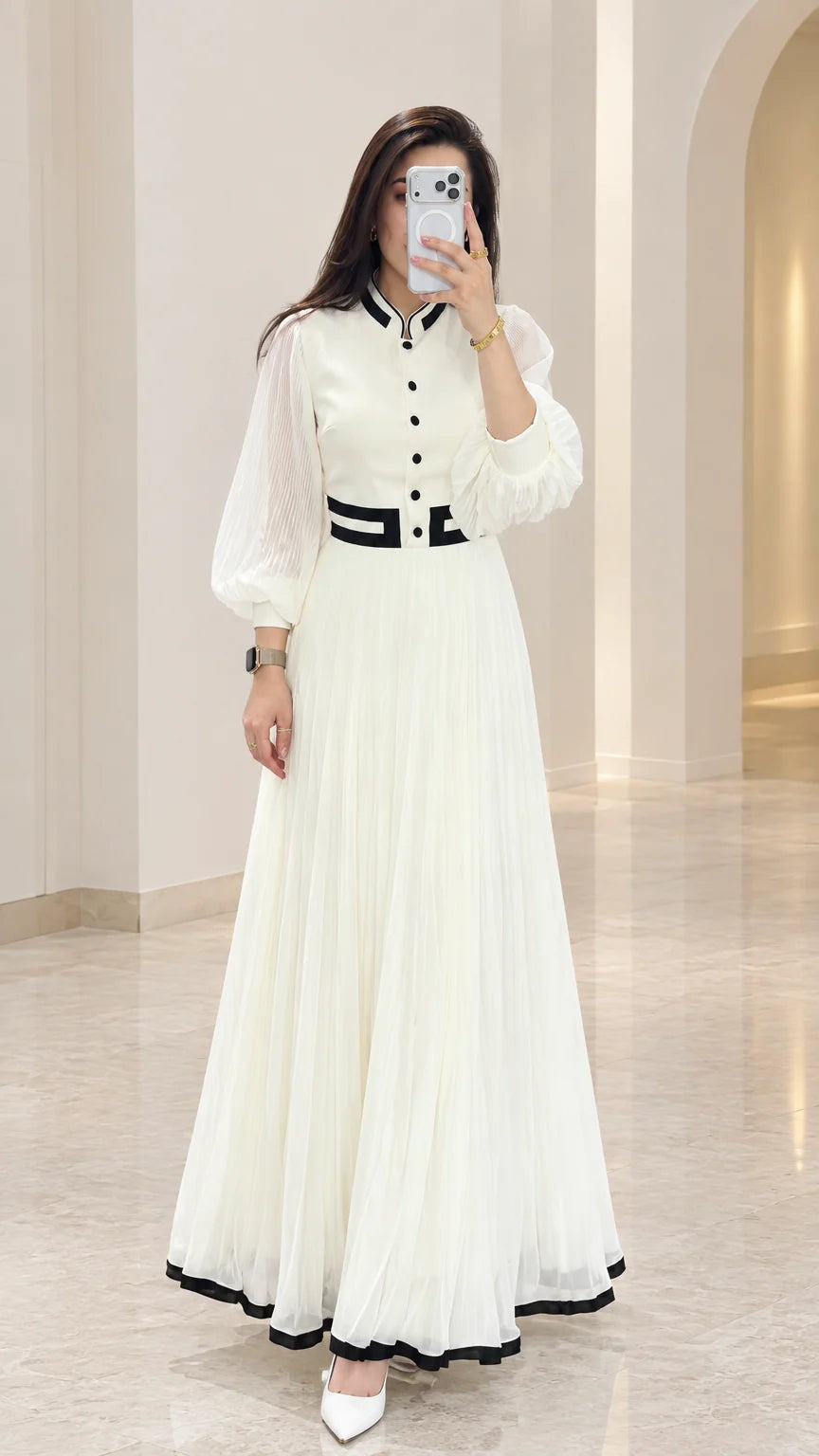 Front full view of white pleated maxi dress with black contrast trim and sheer lantern sleeves