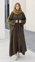 Front view of woman wearing olive green plaid maxi duster coat with matching green scarf