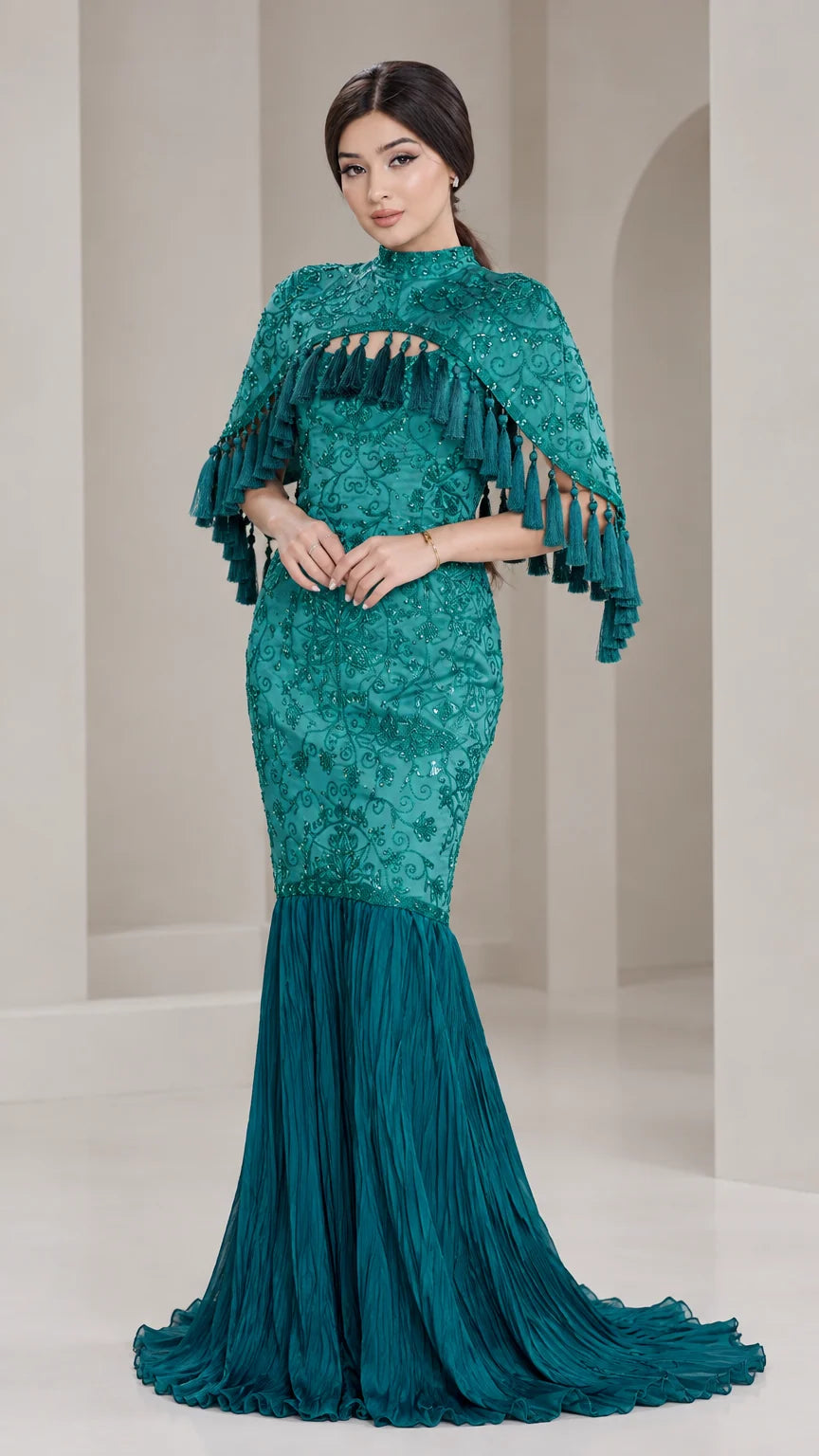 Front view of model wearing Teal Green embroidered cape mermaid gown with tassel trim