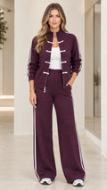 Front full view of woman wearing burgundy knit tracksuit set with side stripes and wide leg pants