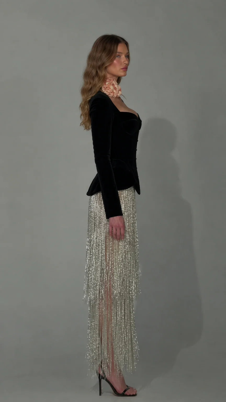 Side profile of black velvet corset evening dress with flowing tassel skirt
