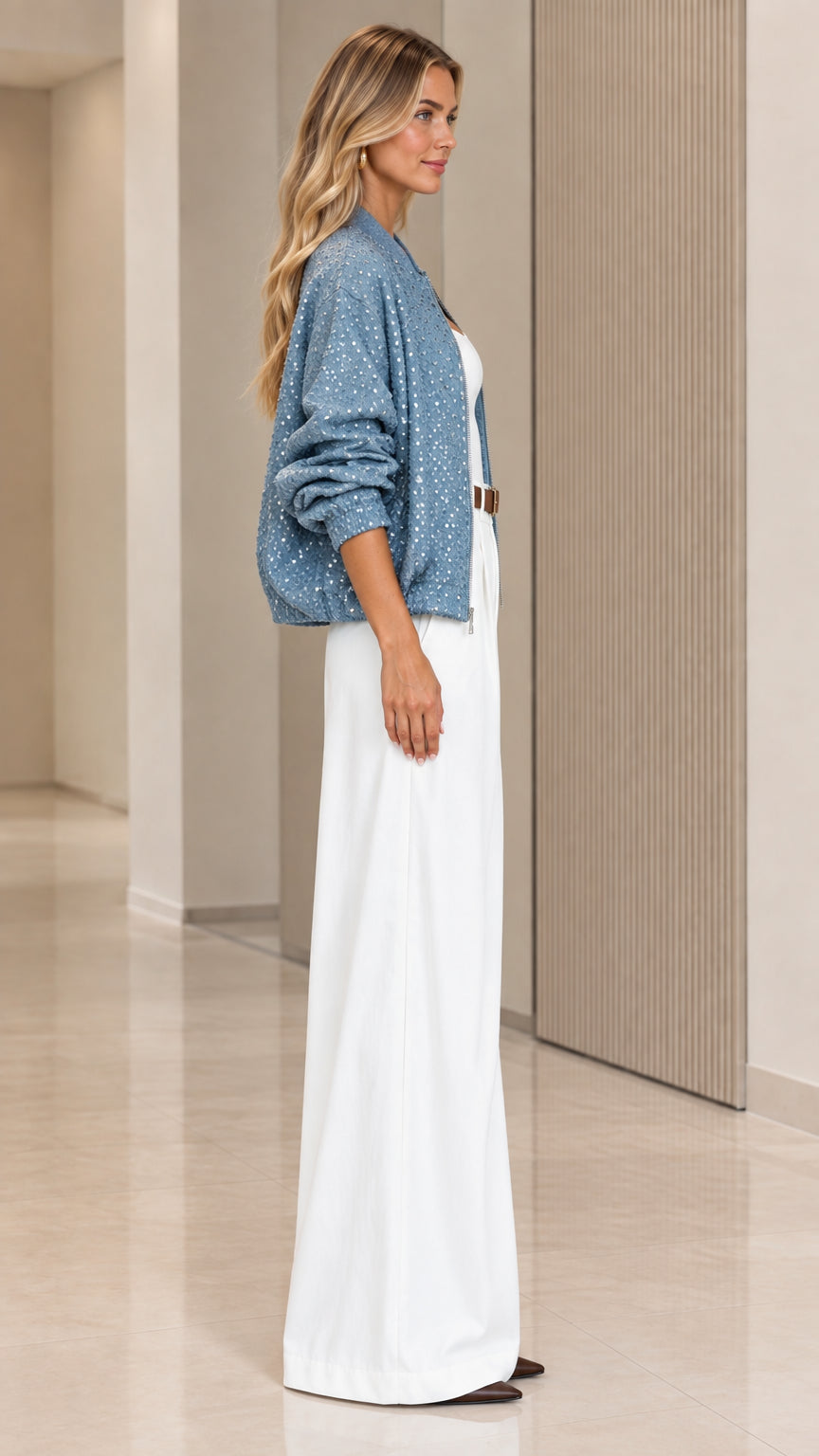 Side profile view of woman modeling dusty blue sparkly zip-up bomber jacket