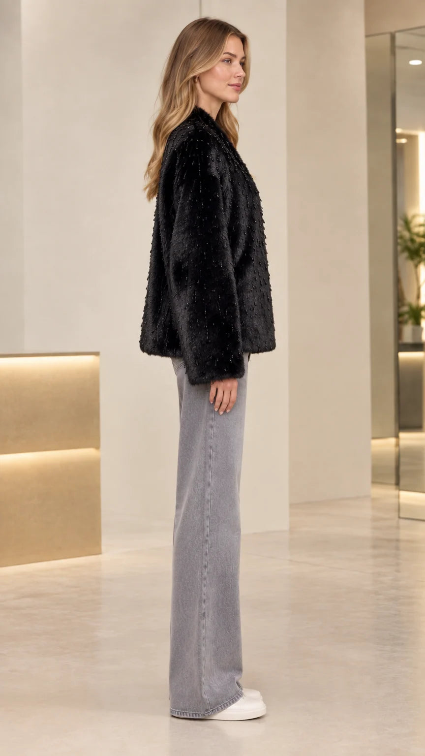 Side profile of model wearing black textured faux fur jacket