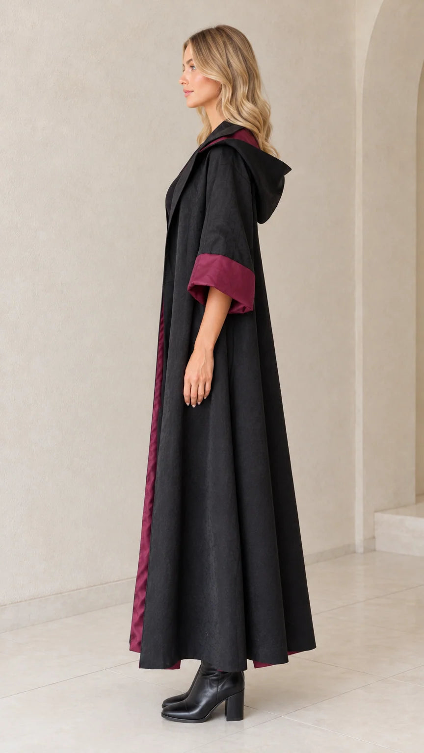Side profile view of black flowing floor-length hooded coat