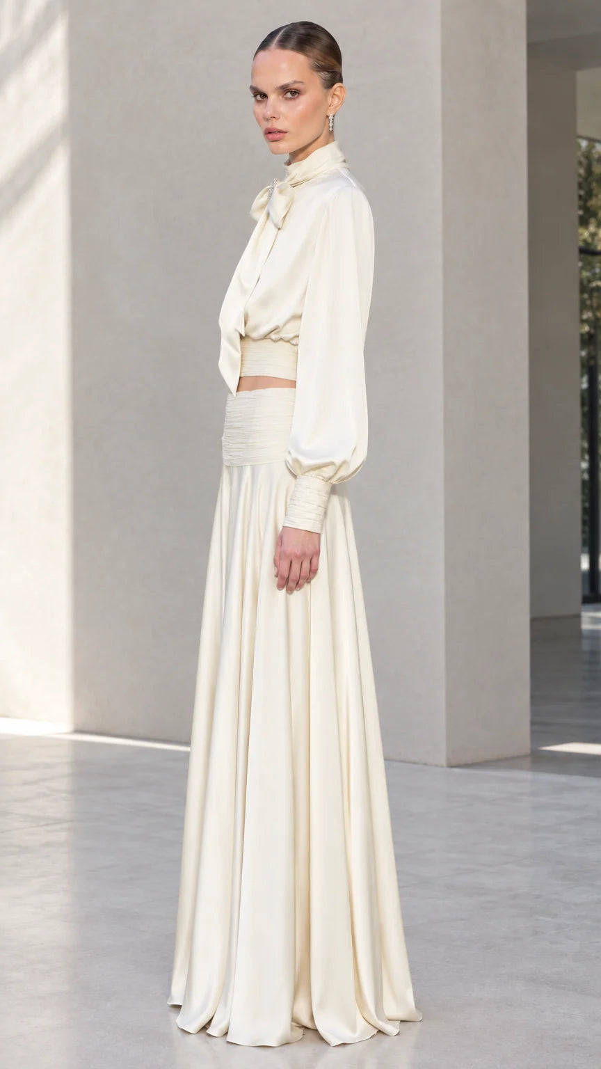 Side profile of model in ivory satin two-piece evening set with bishop sleeves
