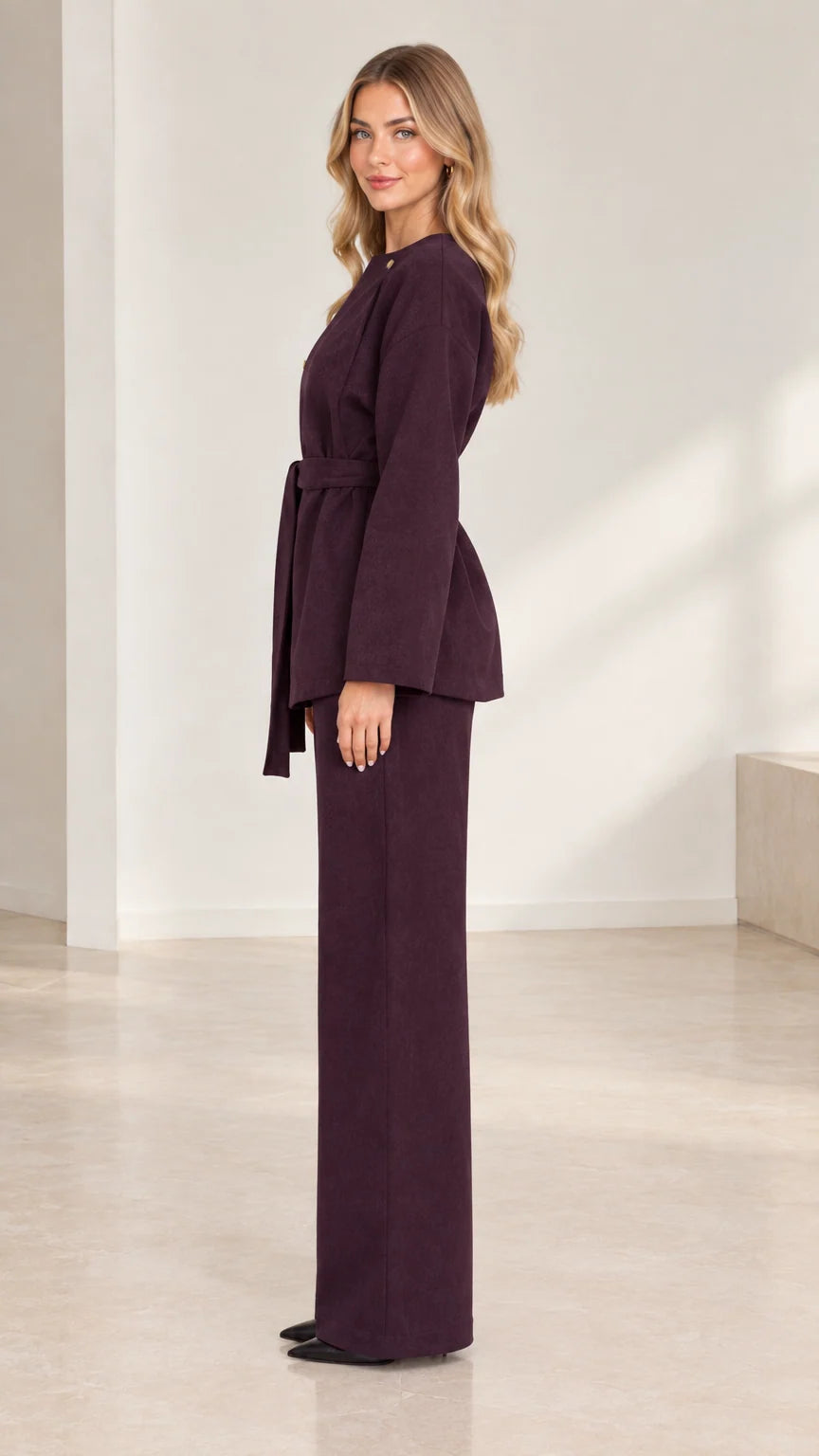 Side profile view of deep plum two-piece belted tunic and tailored wide-leg trousers