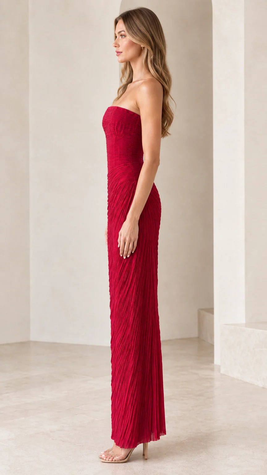 Side profile of model in strapless red pleated column evening gown