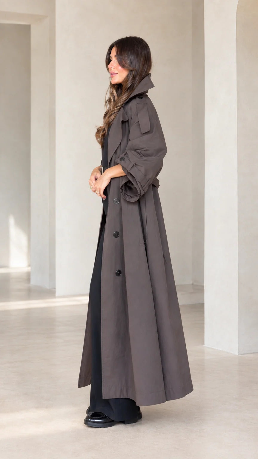Side profile view of woman wearing charcoal brown full-length trench coat