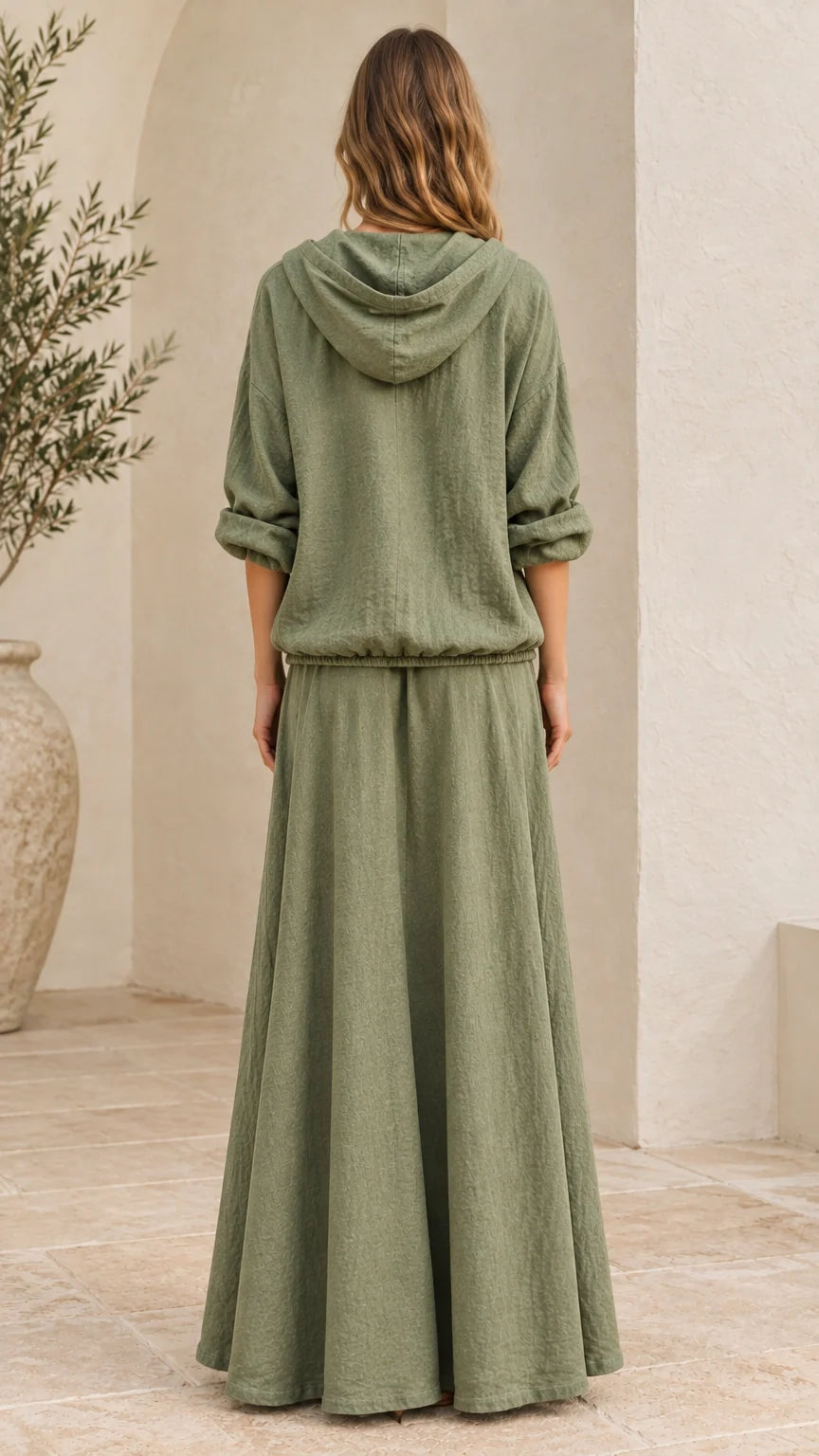 Back view of woman wearing sage green hooded top and long maxi skirt