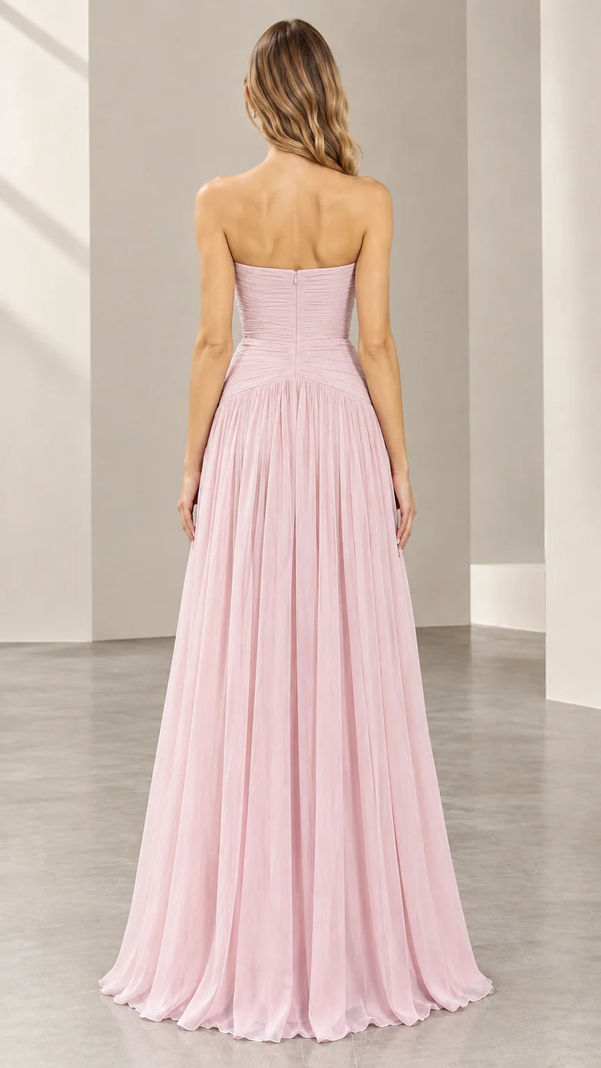 Back view of woman showing the zip-up ruched back and flowing skirt of blush pink gown