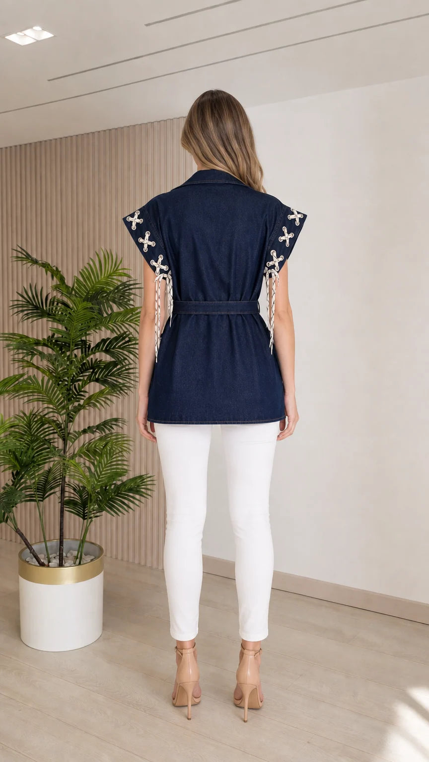 Back view of model wearing the Dark Blue sleeveless denim vest with tied waist belt