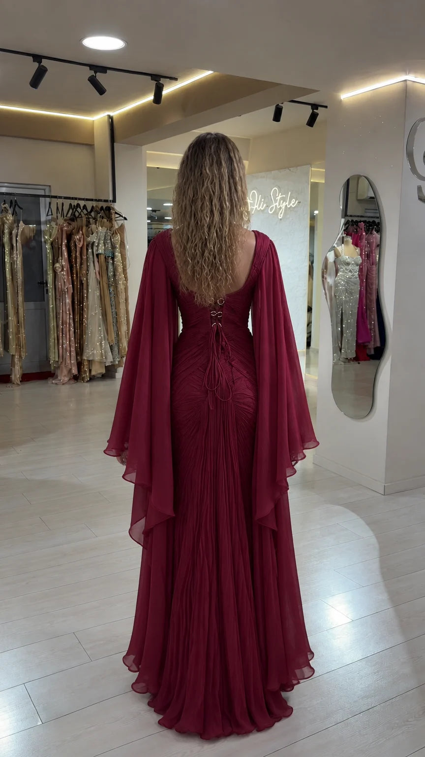 Back view of burgundy maxi gown showing open lace-up corset detail and cape sleeves