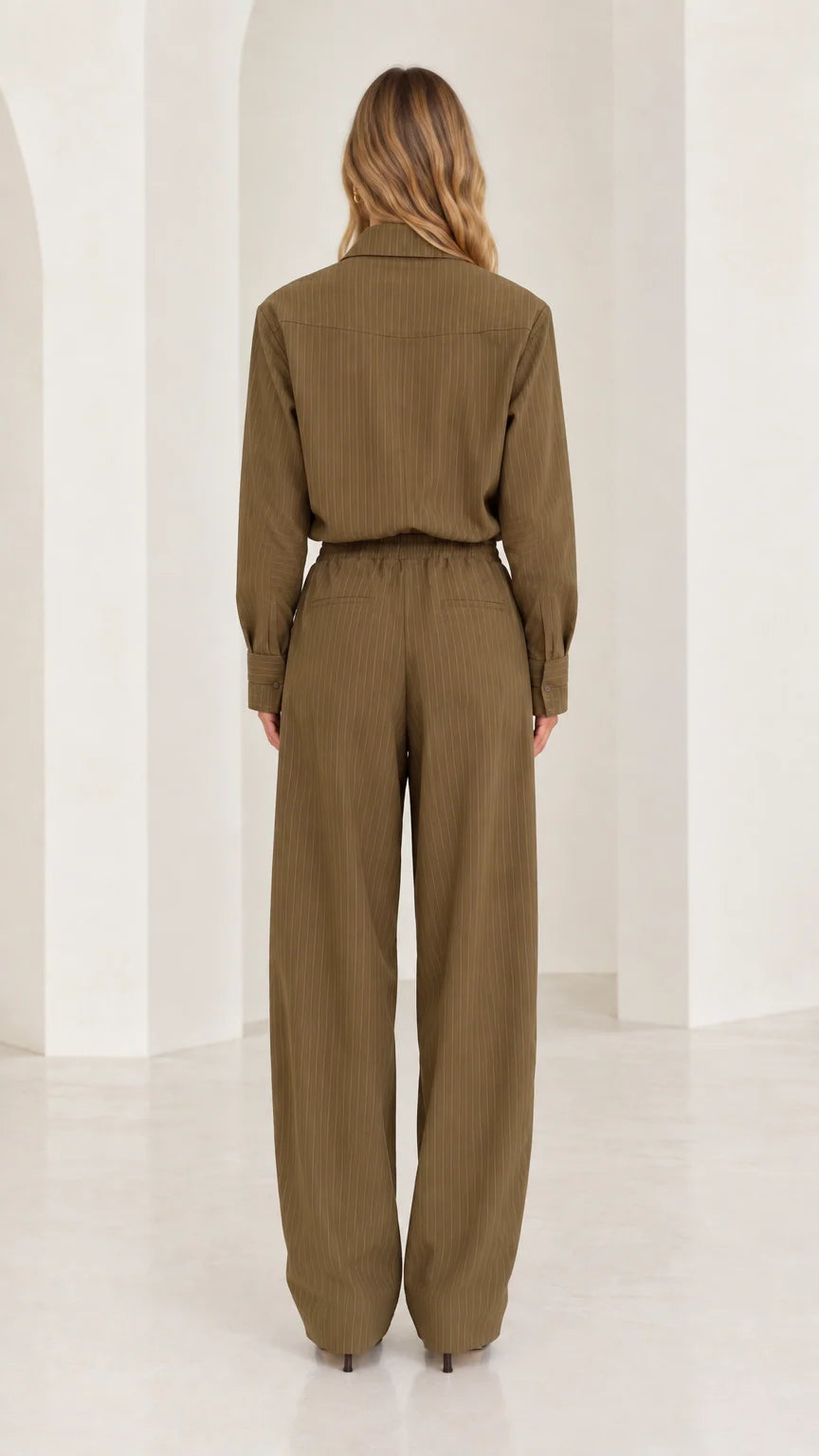 Back full-length view of woman in olive green long sleeve elastic waist jumpsuit
