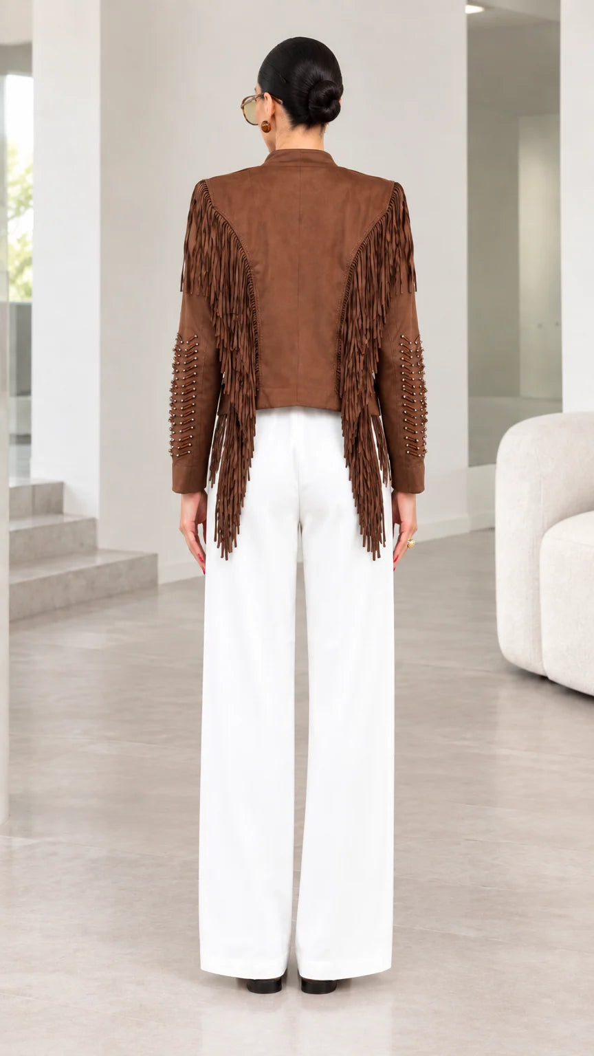 Back view of model showing back yoke fringe detailing on brown jacket