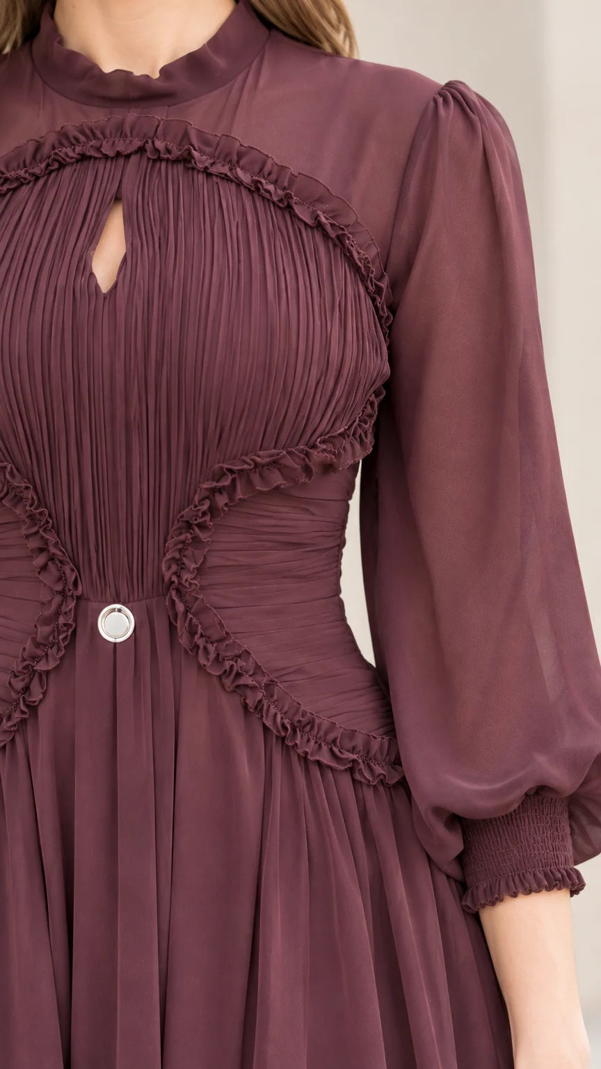 Close-up detail of burgundy bodice showing micro-pleating, keyhole cutout, and ruffle accents
