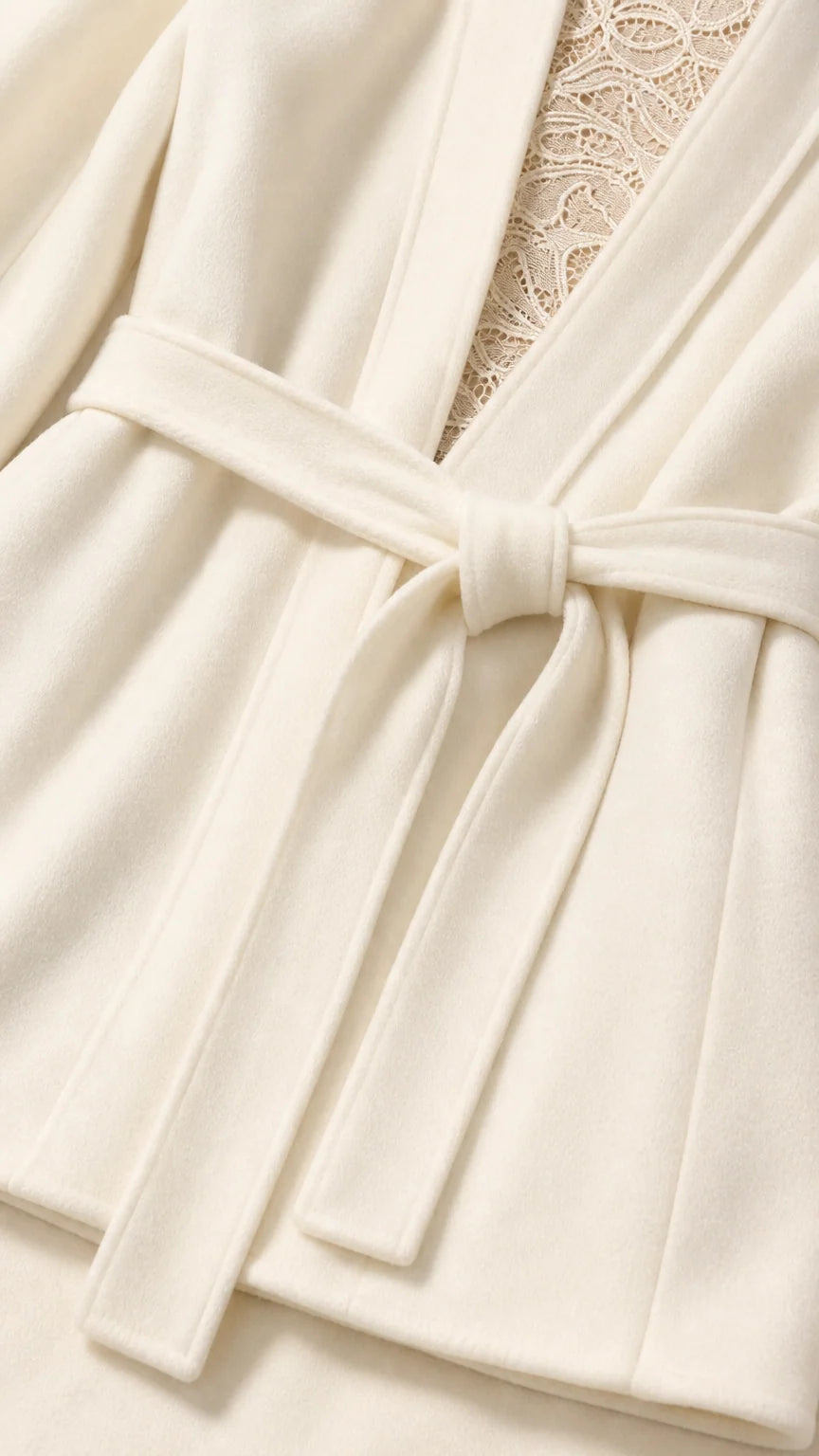Close-up detail of cream blazer fabric, waist belt knot, and lace underlay