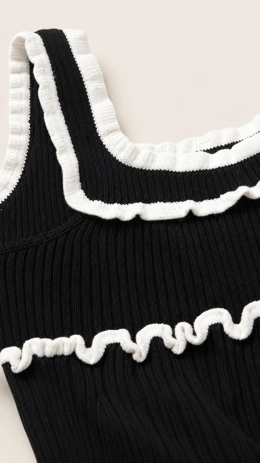 Close-up detail of white lettuce ruffles on black knit top