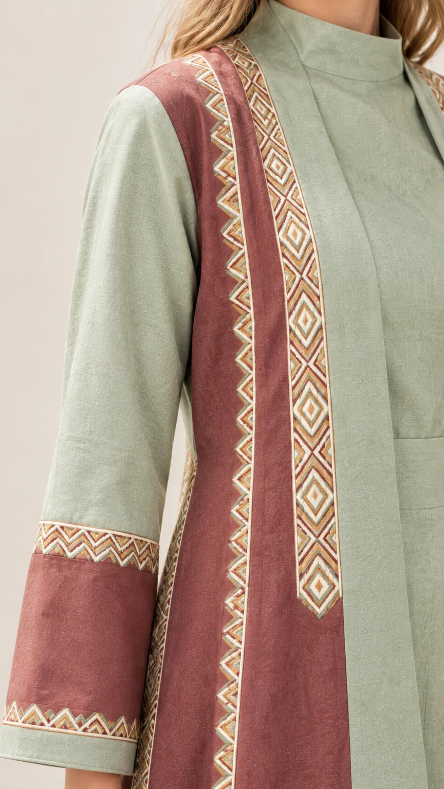 Close-up detail of geometric embroidered trim on abaya collar and sleeve cuff
