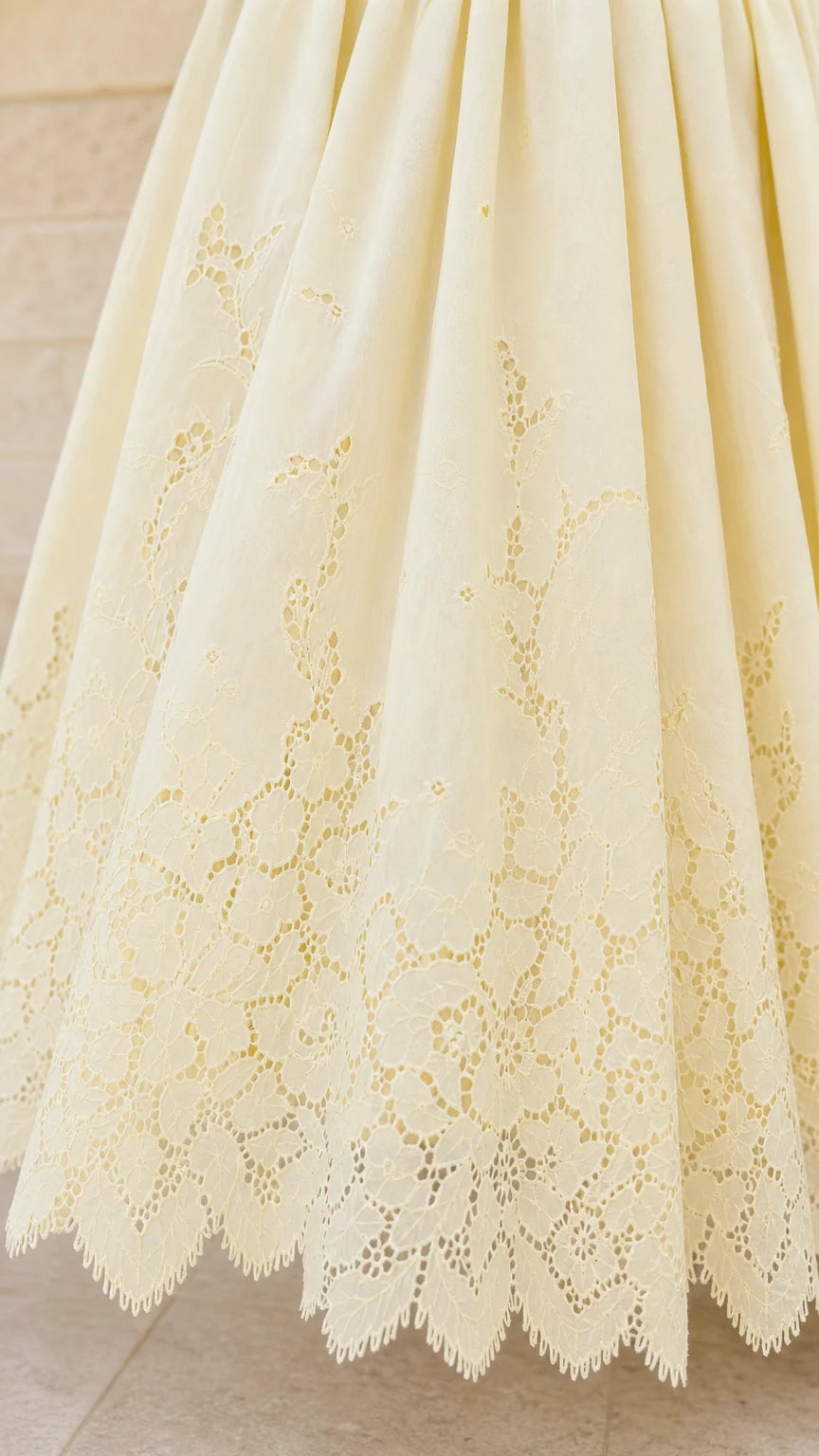 Close-up detail of lace embroidery on yellow dress hem