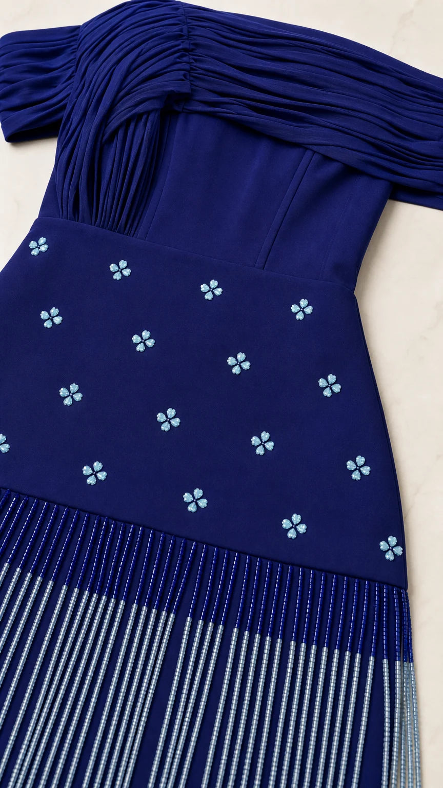 Close-up detail of pleated neckline, beaded floral motifs, and linear fringe on Royal Blue gown