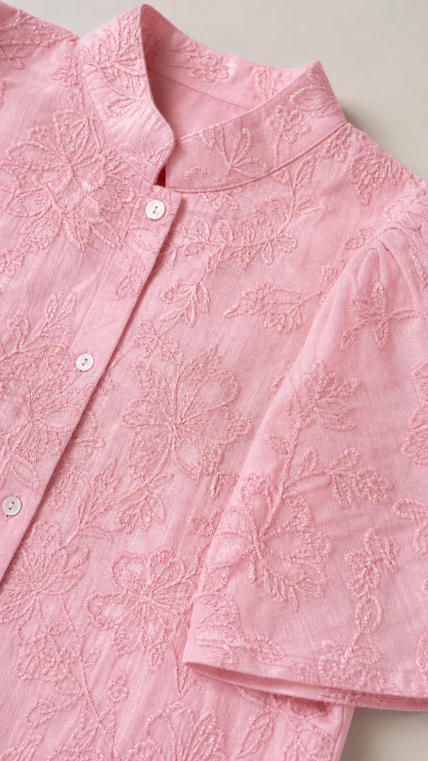 Close-up detail of pink stand collar and intricate floral embroidery on short-sleeve shirt