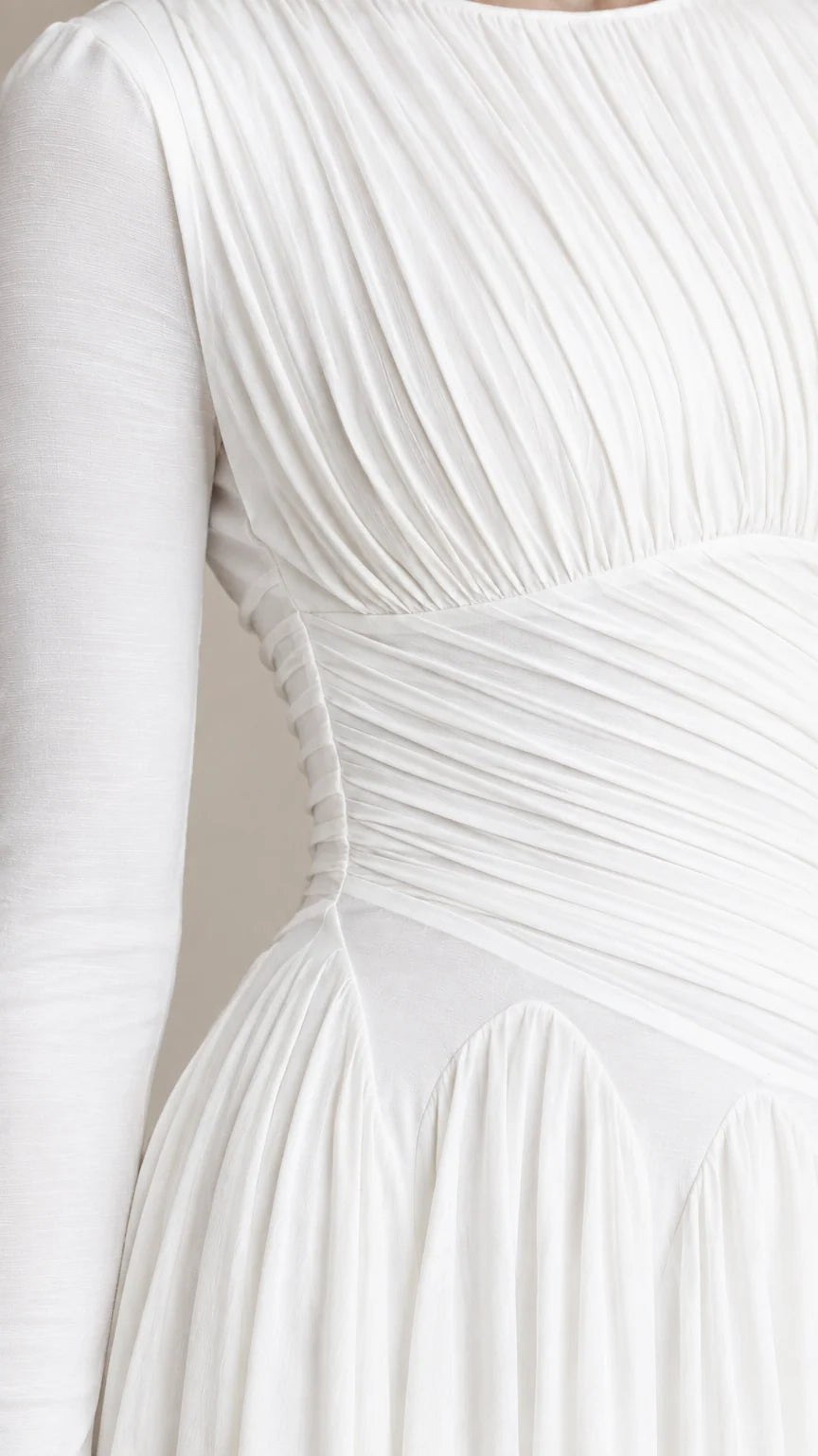 Close-up detail of textured pleating and waist construction on white dress