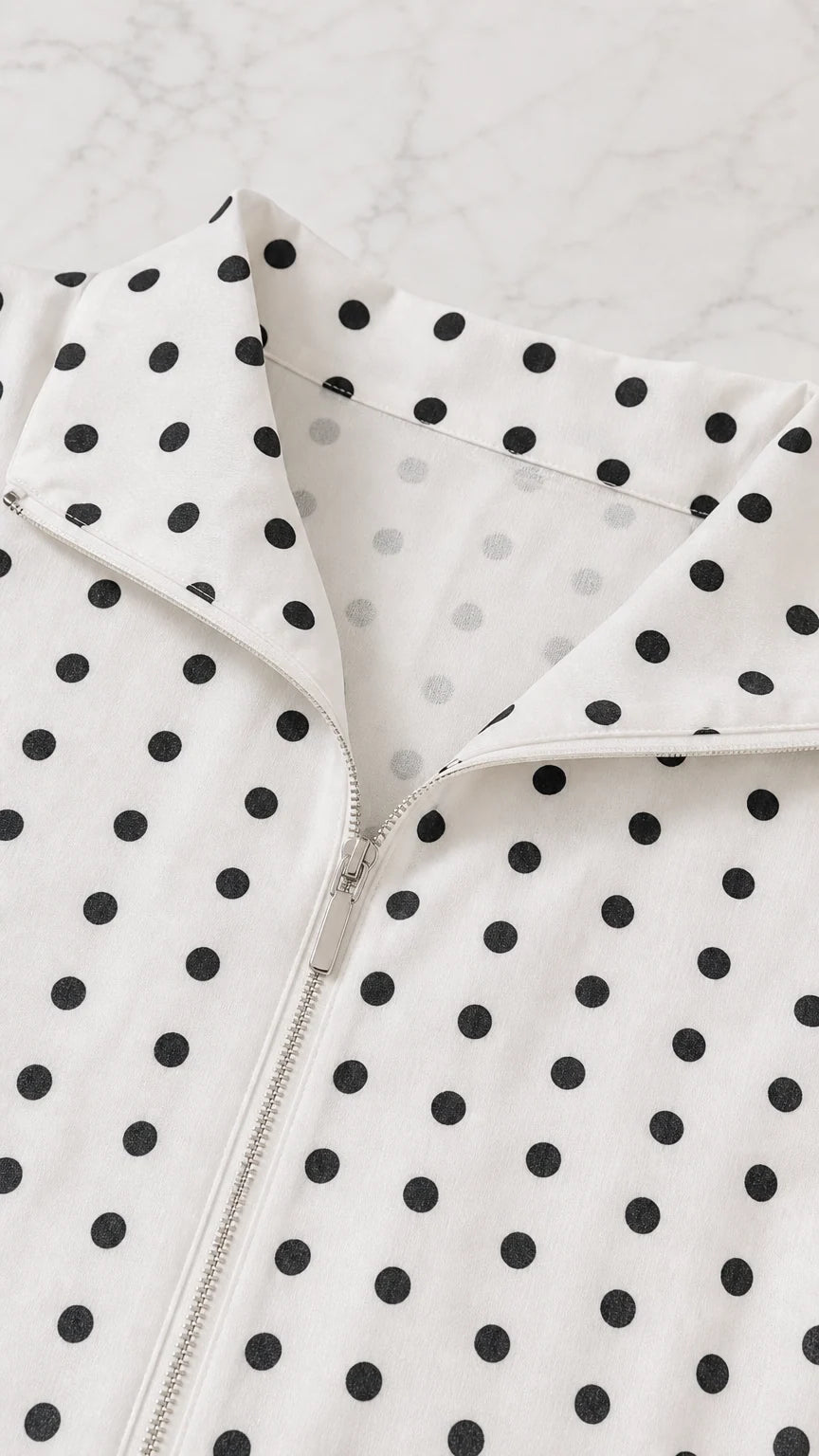 Close-up detail of the spread collar and front zipper on the polka dot top