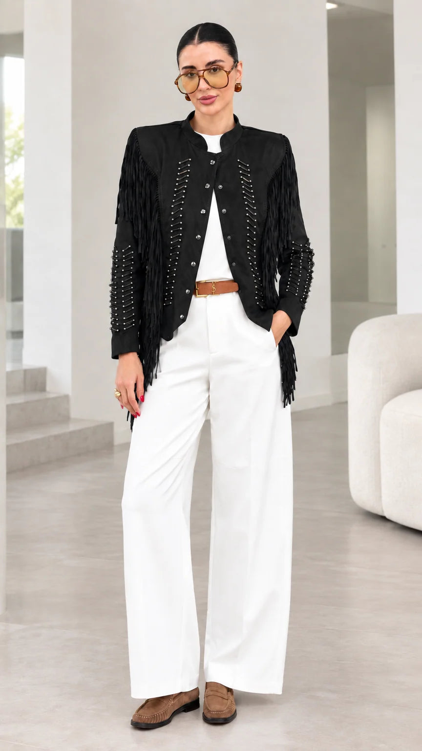 Model wearing black faux suede fringe jacket with white pants