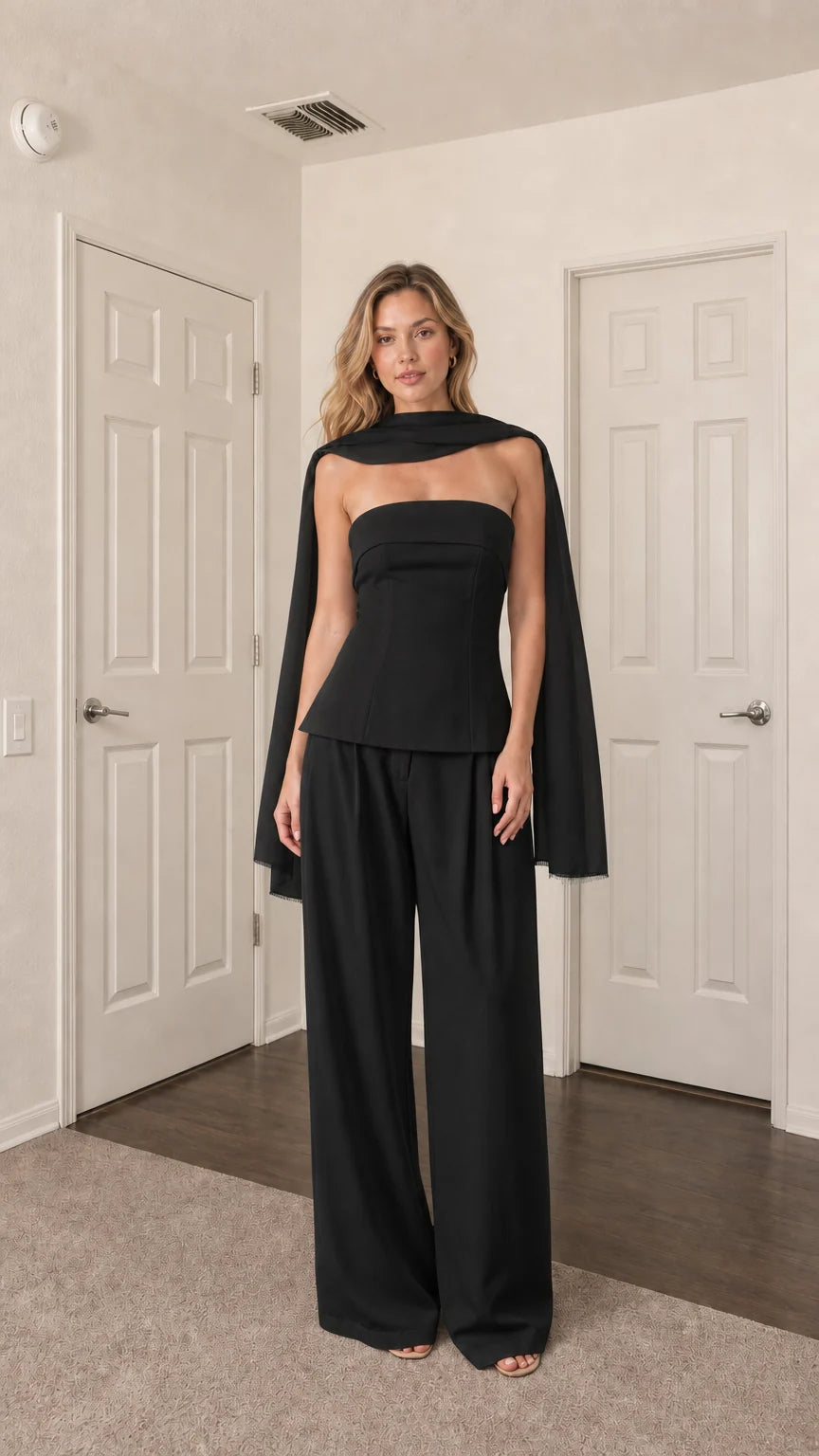 Front view of model wearing black strapless top, wide-leg pants, and scarf