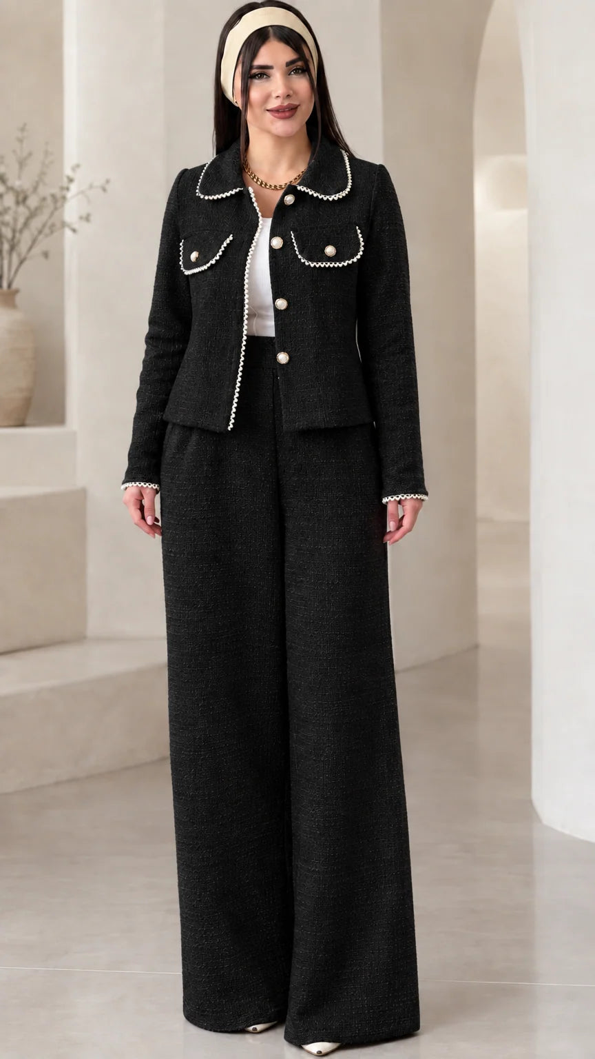 Front view of model wearing the black pearl-trimmed tweed jacket and wide-leg trousers set