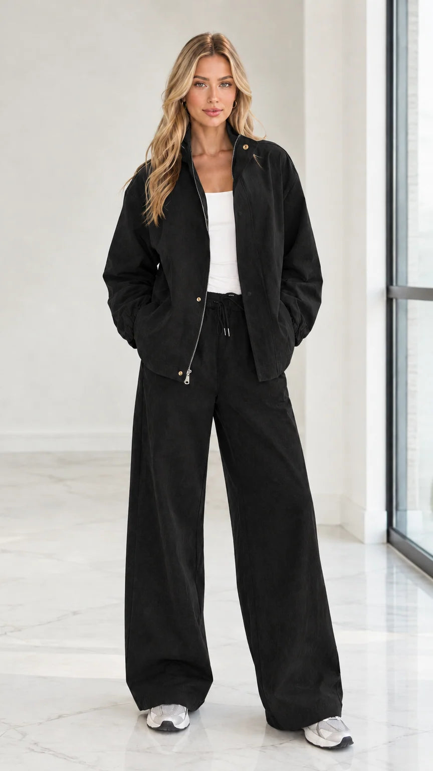 Full front view of woman wearing black 2-piece zip jacket and wide leg pants set