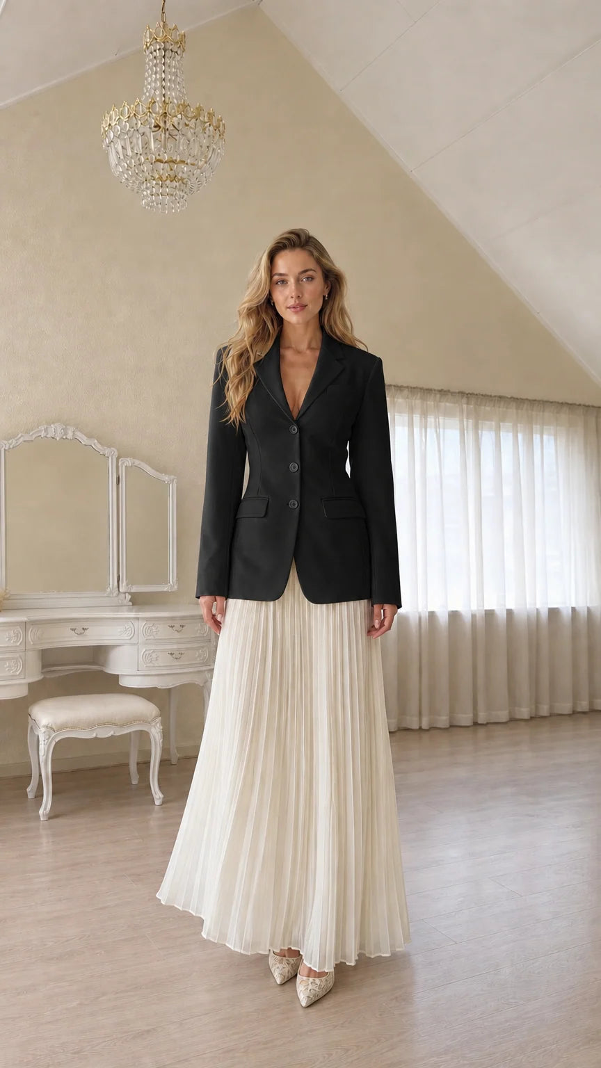 Full length view of a woman wearing a black tailored blazer and pleated skirt
