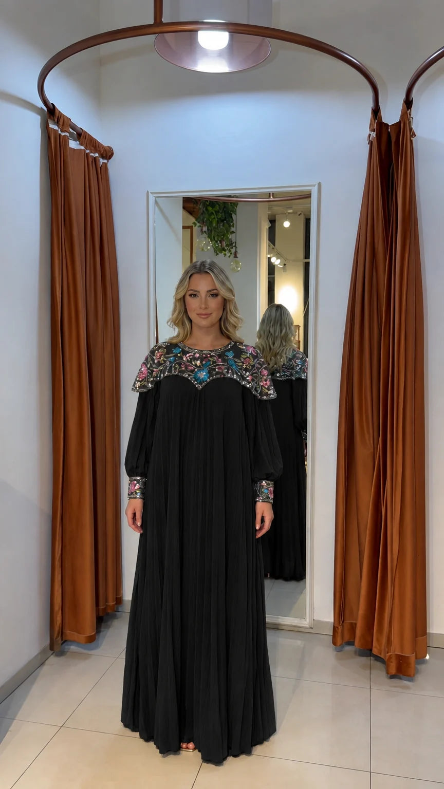 Woman wearing black pleated long-sleeve maxi dress with beaded yoke