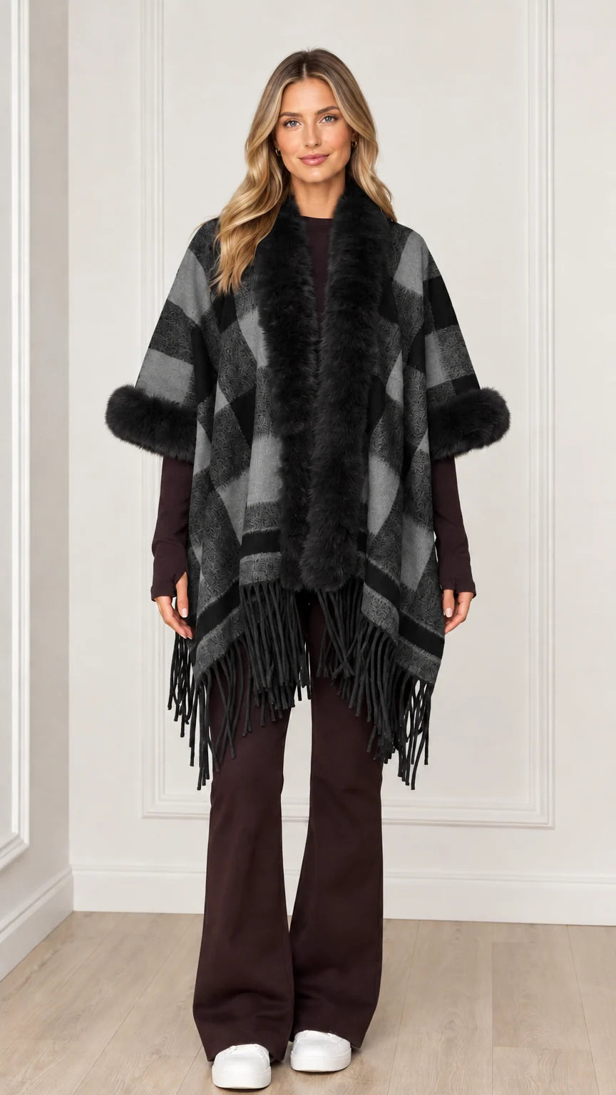 Woman wearing charcoal grey plaid poncho wrap with black faux fur trim