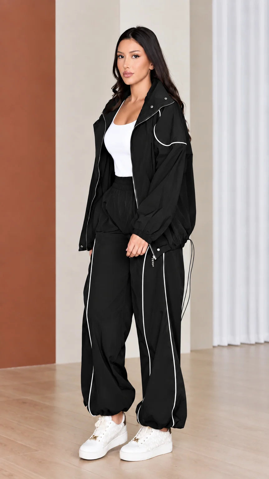 Full-length view of woman modeling black windbreaker tracksuit set with white piping