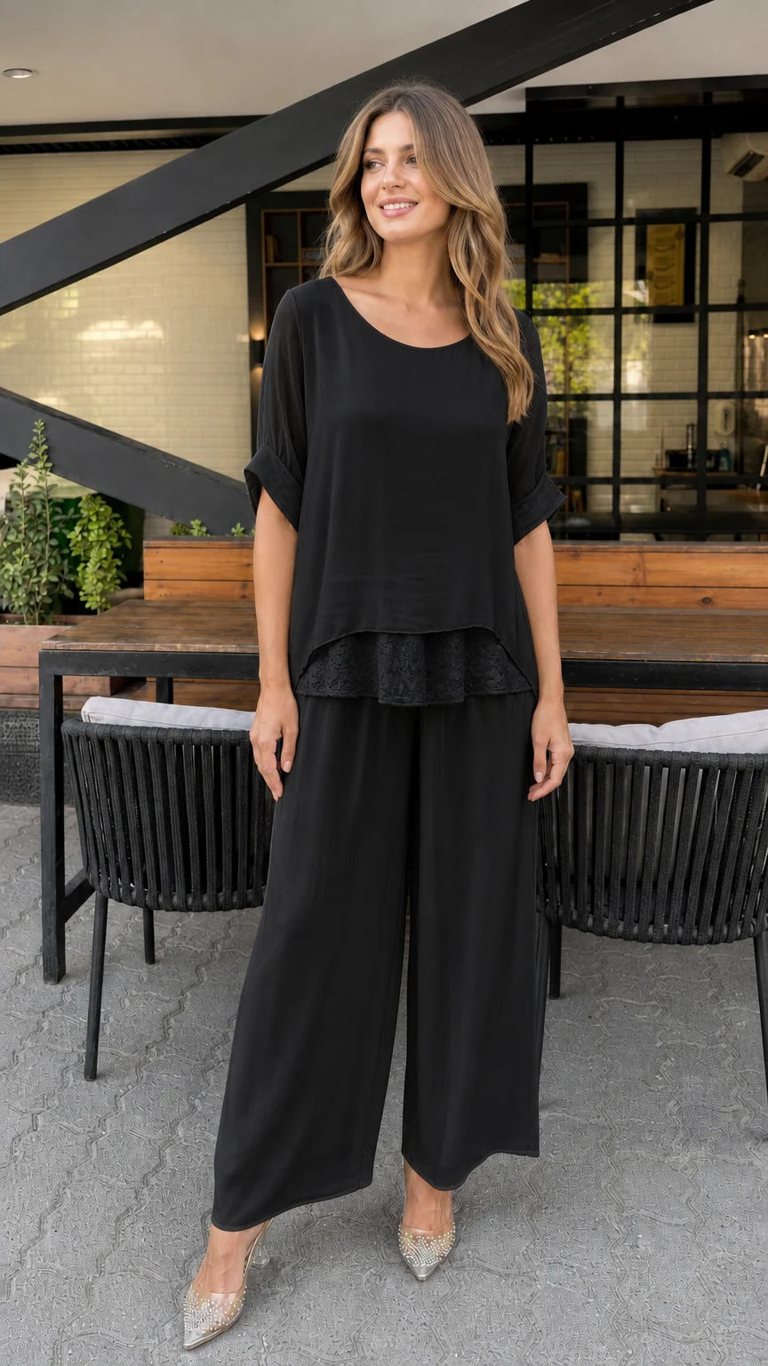 Model wearing black layered tunic and wide-leg pants set