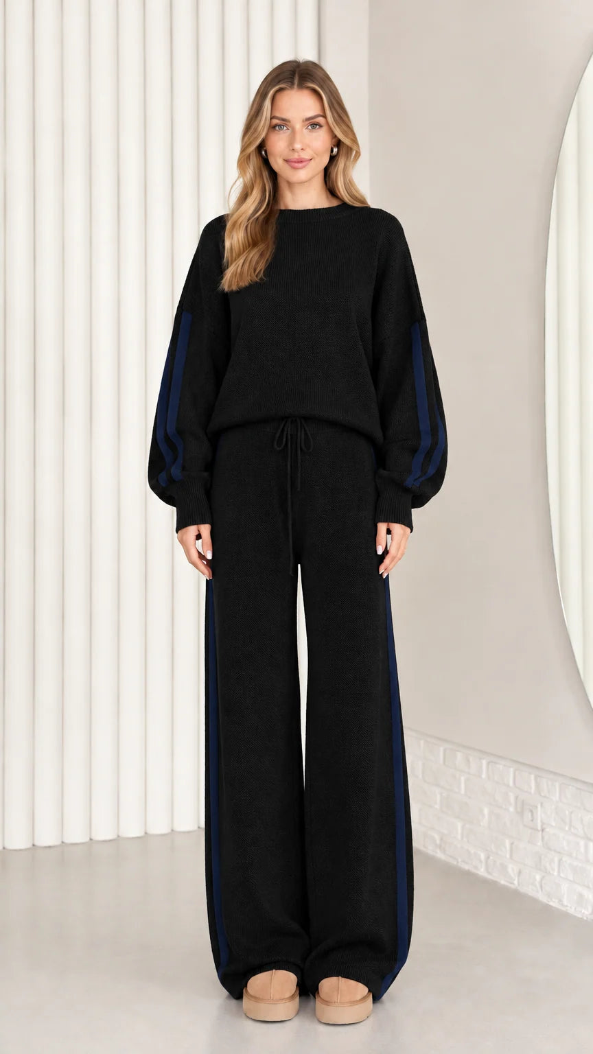 Front view of model wearing black knit two-piece lounge set with navy side stripes