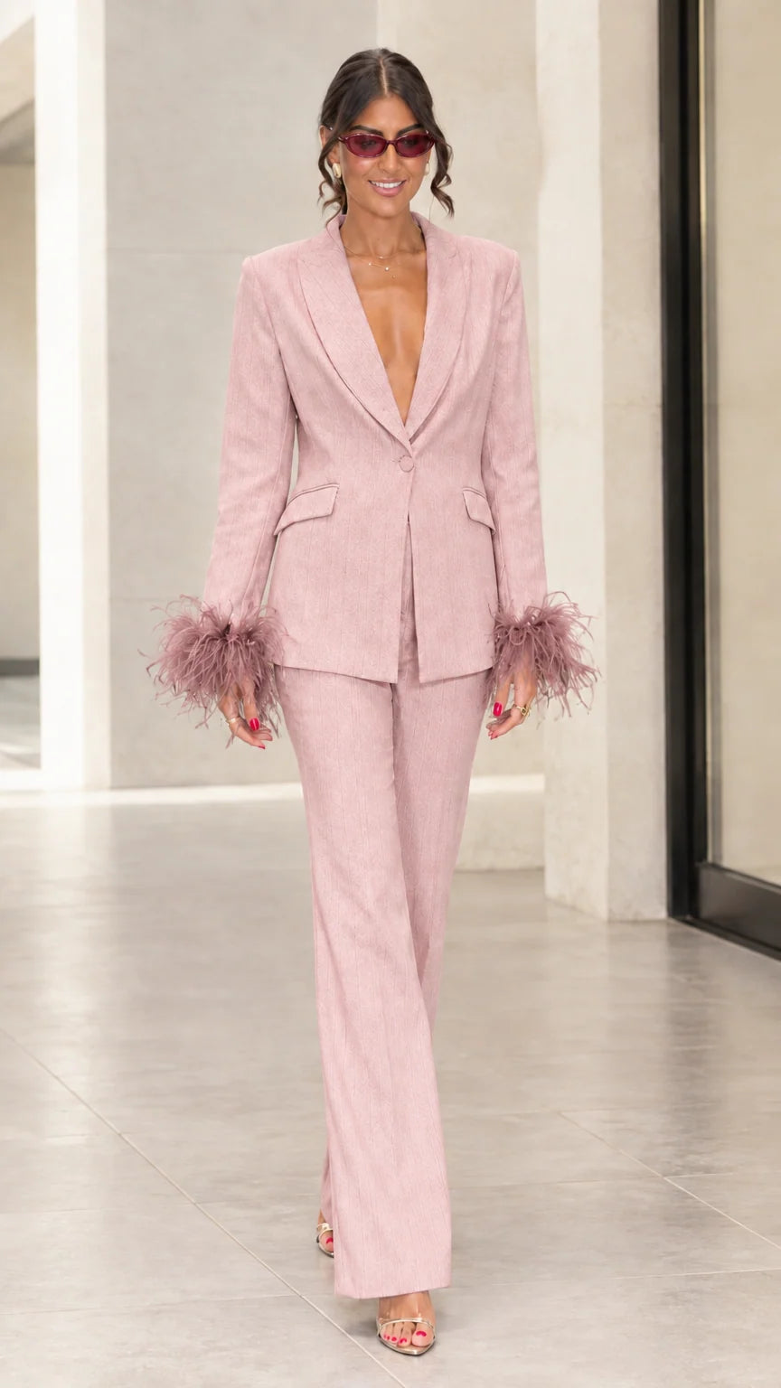 Front view of woman wearing blush pink tailored suit set with tonal feather cuffs