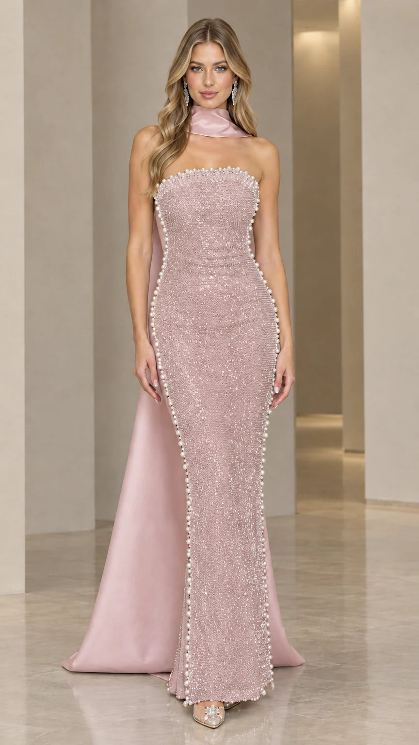 Model wearing blush pink beaded column maxi dress with flowing pink scarf train
