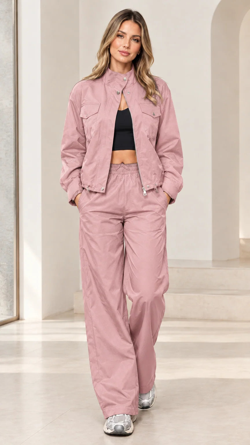 Full-length studio shot of woman wearing dusty pink zip-up windbreaker track set