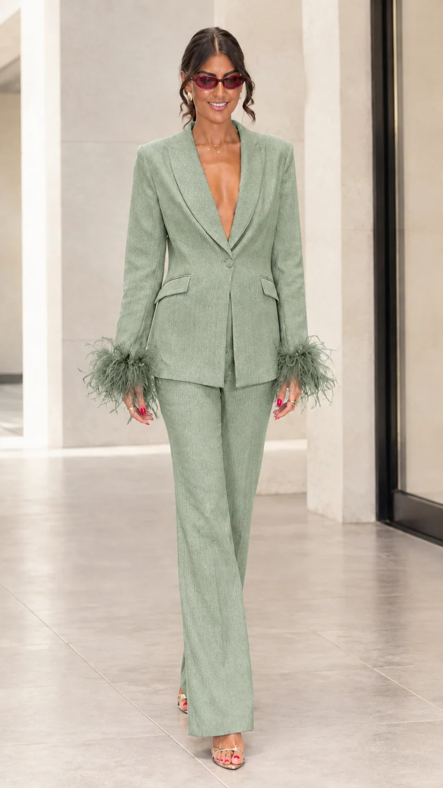 Front view of woman wearing sage green tailored suit set with green feather cuffs