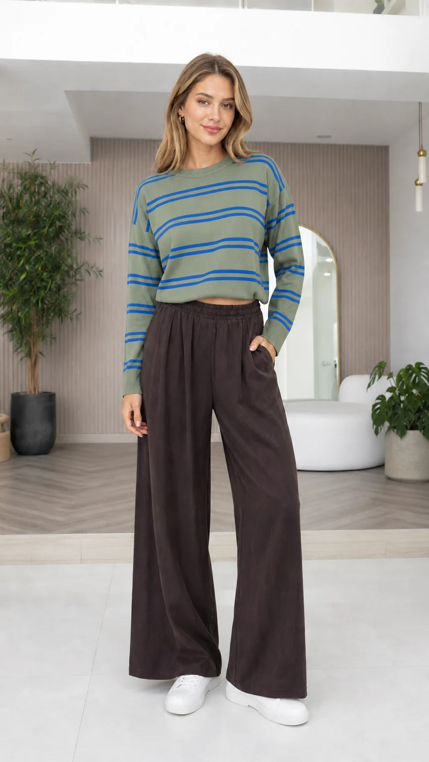 Model wearing sage green and blue striped knit pullover with wide-leg trousers