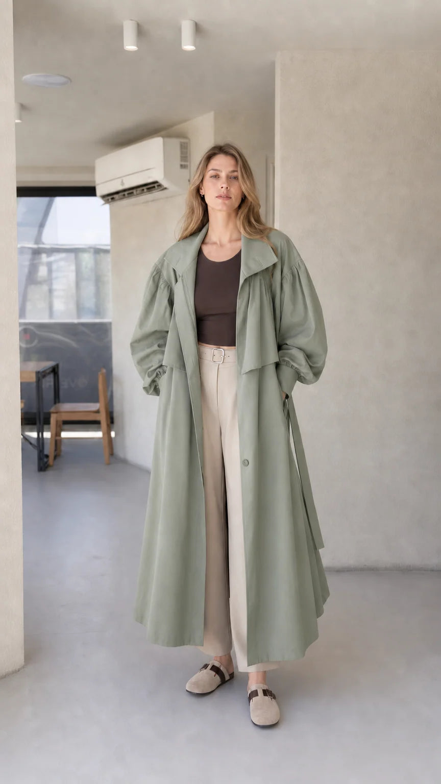 Model wearing sage green oversized maxi trench coat with removable waist belt
