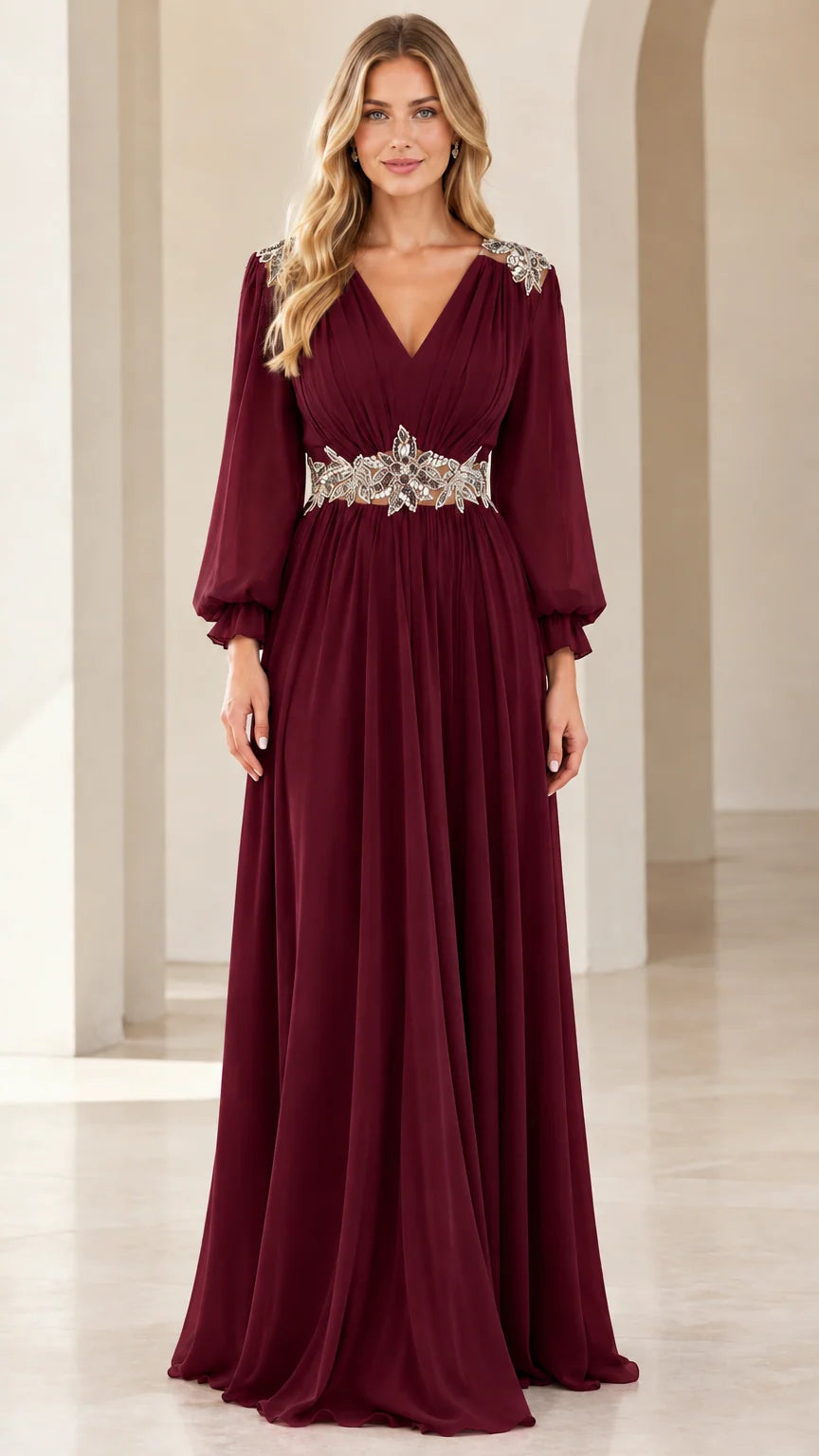 Front view of woman wearing burgundy long-sleeve chiffon evening gown with crystal waistband